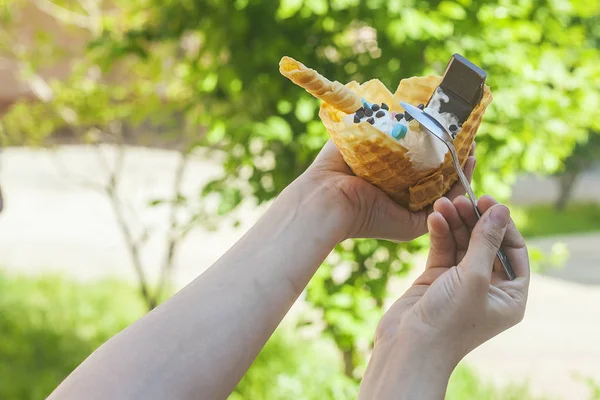 Jonge vrouw met heerlijk ijs met wafel tijdens een picknick in de natuur. Zomer voedsel concept. Jong volwassen eten lekker ijs met een stok op een heldere zomerdag. — Stockfoto