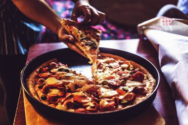 Bir parça pizza alan kişinin eli