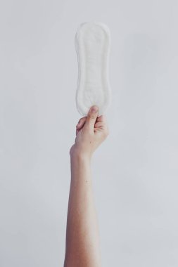 Beyaz arka plana hijyenik ped asan bir kadın. Kadınsı adet döngüsünü gösteren dönem konsepti.