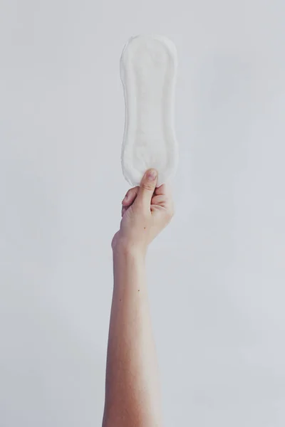 Mujer colgando almohadilla sanitaria contra fondo blanco. Concepto de días de período que muestra el ciclo menstrual femenino . — Foto de Stock