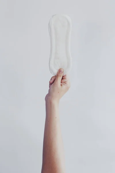 Woman hanging up sanitary pad against white background. Period days concept showing feminine menstrual cycle. — Stock Photo, Image