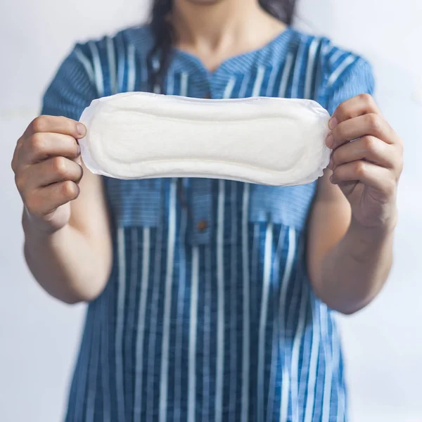 Female's hygiene products. Woman in medical gloves holding sanitary pads against white background. Period days concept showing feminine menstrual cycle. — Stock Photo, Image