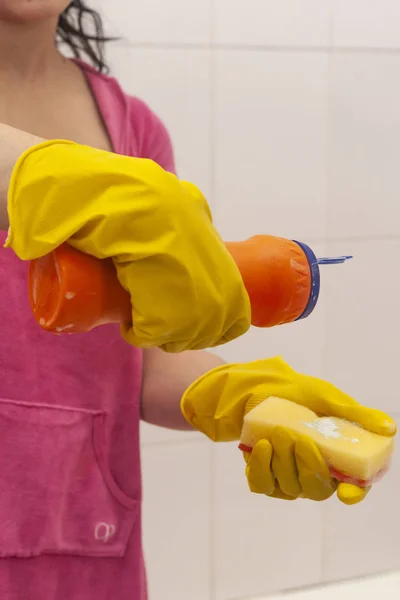 Mujer joven equipada con botella de limpiador químico y esponja. Concepto de limpieza y limpieza. Las mujeres se preparan para limpiar el baño — Foto de Stock