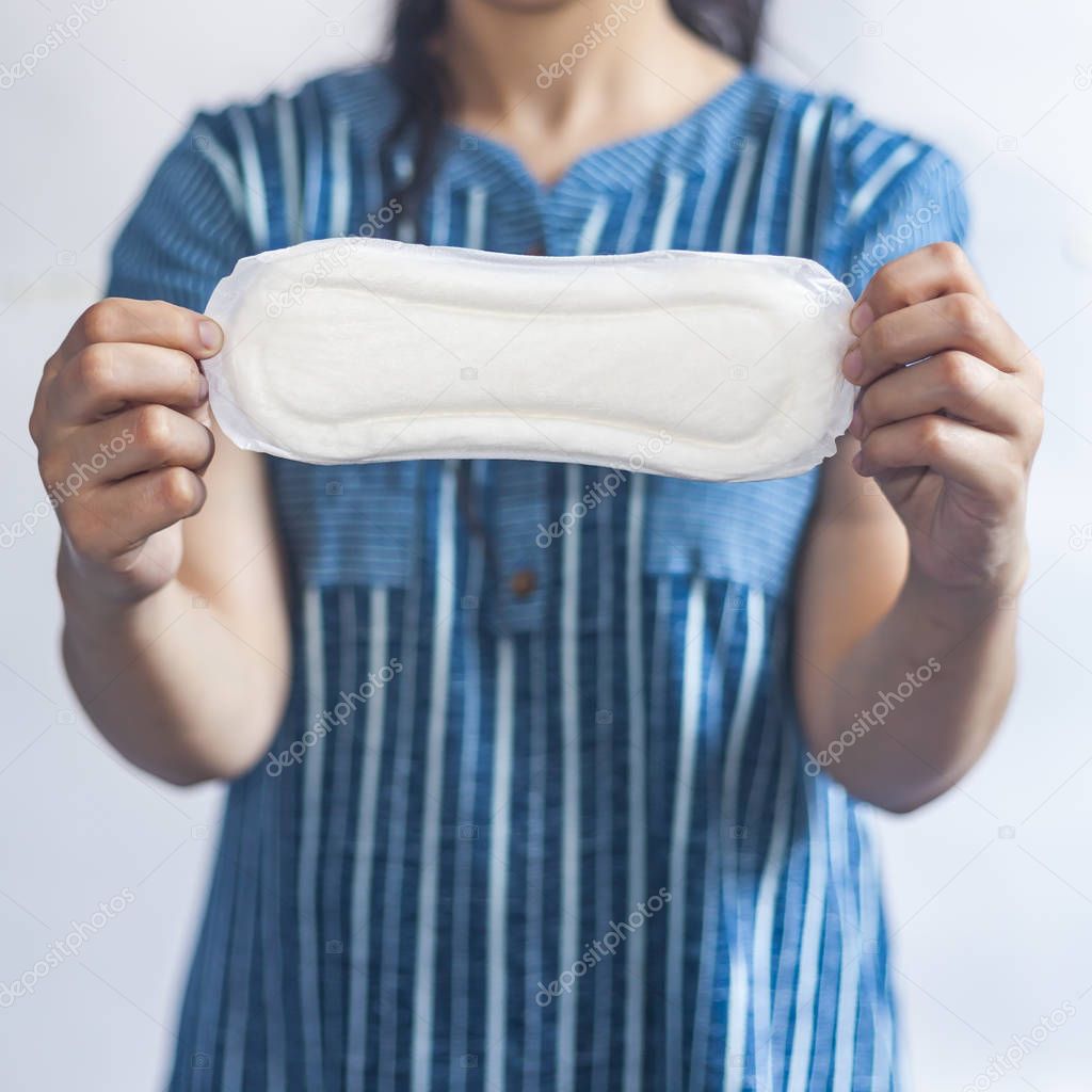 Female's hygiene products. Woman in medical gloves holding sanitary pads against white background. Period days concept showing feminine menstrual cycle.