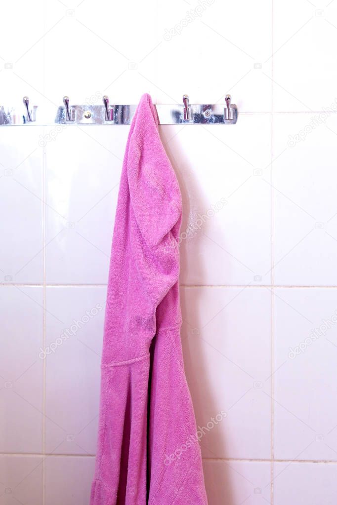 Female's pink bathrobe hanging on hook