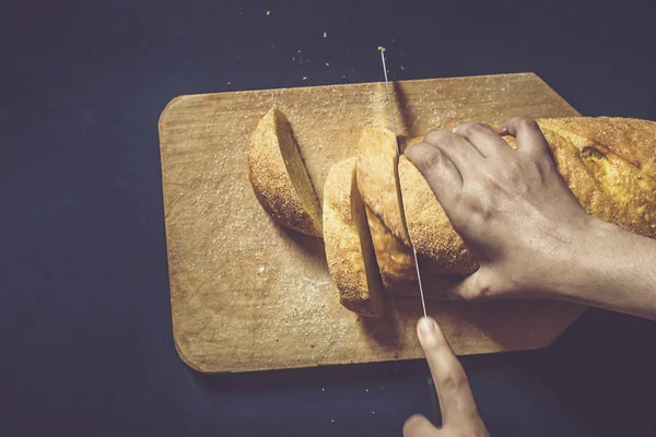 Konsep makanan. Tangan memotong roti. Mengiris roti. Tampilan atas . — Stok Foto
