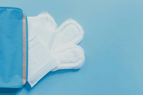 Produtos de higiene feminina. Saco feminino e almofadas sanitárias em fundo azul — Fotografia de Stock