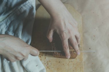 Ev hanımı ekmek kesiyor. Kadın kesme tahtasında ekmek kesti. Yukarıdan görüntüleyin. Ekmeklerin en iyi görünümü