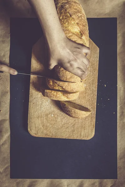 Η ιδέα του φαγητού. Χέρι κοπής ψωμί. Κόβω ψωμί. Κορυφαία προβολή. — Φωτογραφία Αρχείου