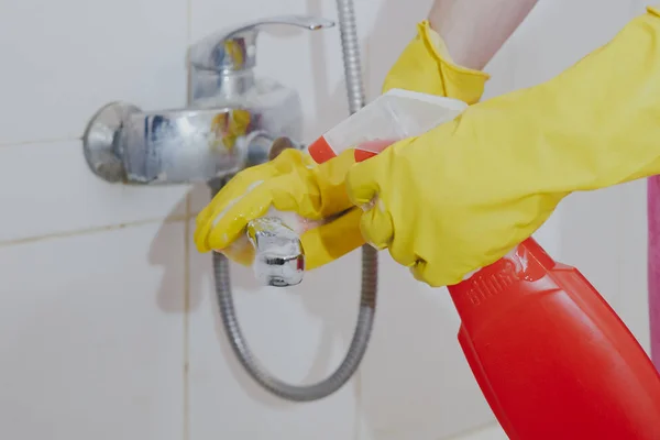 Домогосподарка прибирає кран для ванної та душу. Покоївка в жовтих захисних рукавичках, що миють брудний кран для ванни. Руки жінки миють ванну — стокове фото