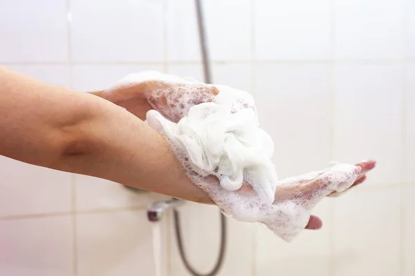 Mujer lavándose las manos con una esponja en el baño. Brazos de lavado femeninos con una esponja espumosa en el baño. Cuidado corporal y concepto limpio — Foto de Stock
