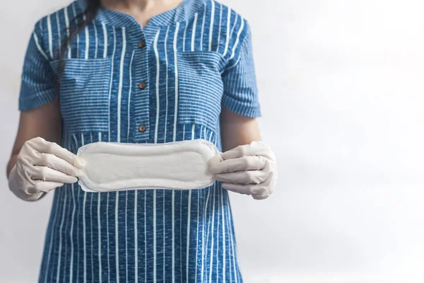 Productos de higiene femenina. Mujer con guantes médicos sosteniendo toallas sanitarias sobre fondo blanco. Concepto de días de período que muestra el ciclo menstrual femenino . — Foto de Stock