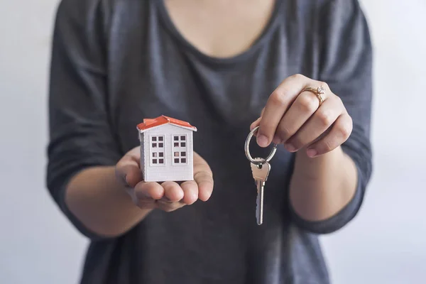 Woman holding miniature toy house and keys. Real estate agent holding keys and toy house. Buying or selling real estate — 스톡 사진