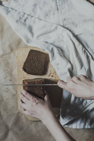 Ibu rumah tangga memotong roti. Perempuan memotong roti di papan potong. Lihat dari atas. Tampilan atas roti — Stok Foto