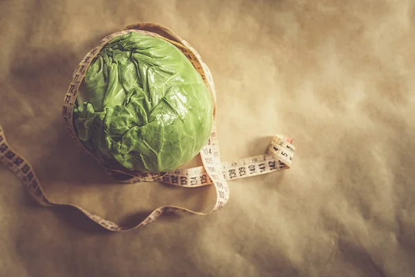 Verse groene kool groente met meetlint op bruin papier achtergrond — Stockfoto