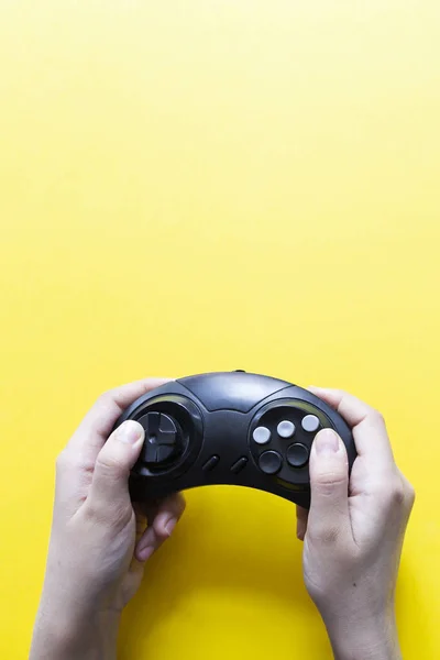 Vista vertical a las manos sosteniendo gamepad negro y jugando videojuego contra amarillo — Foto de Stock