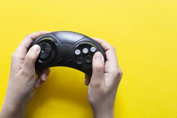 Mano masculina sostiene un joystick para videojuegos sobre un fondo amarillo. Gamepad en la mano del hombre sobre un fondo amarillo — Foto de Stock