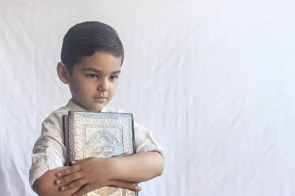 Um jovem rapaz do Médio Oriente com o Alcorão Sagrado. Retrato de uma criança muçulmana de 5 anos segurando um Alcorão sagrado com fundo branco. Espaço livre — Fotografia de Stock