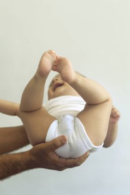 Babam 6 aylık erkek bebeği beyaz arka plana dayadı. Babam bebeğini alıyor. Kopya alanı. Aile kavramı
