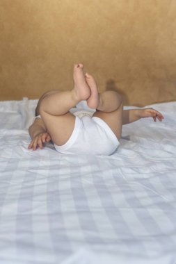 6-8 aylık erkek bebek yatakta eğlenceli bir şekilde yatıyor. Beyaz bodysuit büyüleyici 6-7 aylık küçük bebek. Beyaz yataklı bebek. Kopyalama alanı