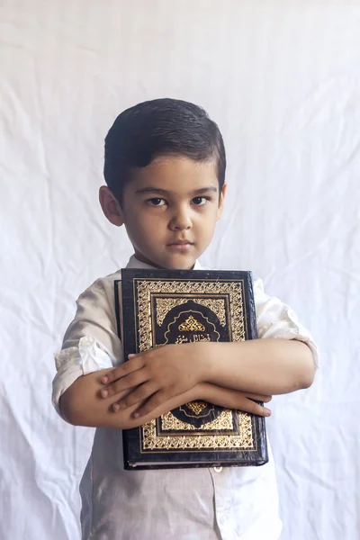 Um jovem rapaz do Médio Oriente com o Alcorão Sagrado. Retrato de uma criança muçulmana de 5 anos segurando um Alcorão sagrado com fundo branco. Espaço livre — Fotografia de Stock