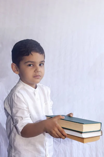 De vuelta al concepto escolar. Lindo chico de Oriente Medio sosteniendo una pila de libros sobre el fondo blanco. Retrato del niño de Asia Central preparándose para ir a la escuela — Foto de Stock