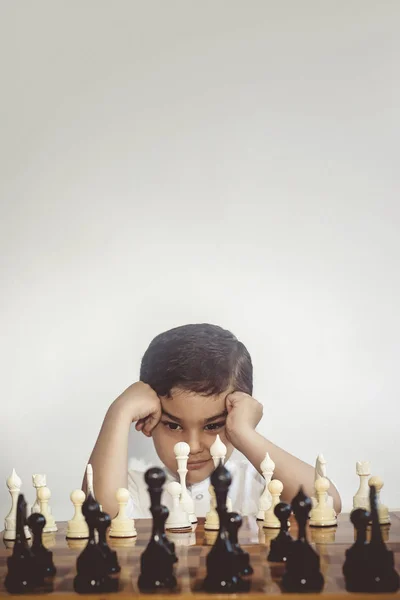 Rapaz atencioso a jogar xadrez. Um miúdo do Médio Oriente joga xadrez. Pensando em encontrar o melhor movimento — Fotografia de Stock