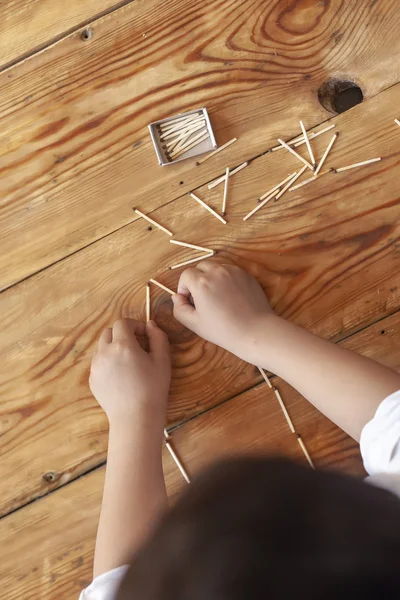 Chłopiec gra z Matchsticks. Młode dziecko gra mecz laski na drewnianym tle. — Zdjęcie stockowe