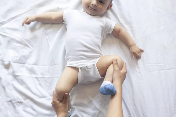 Baby massage. Mam doen gymnastiek met Kid. Mama masserende schattige baby jongen. Bewegende baby's benen om constipatie te helpen verlichten. Jonge moeder doet oefeningen en bewegingen om baby's darmen te stimuleren. — Stockfoto