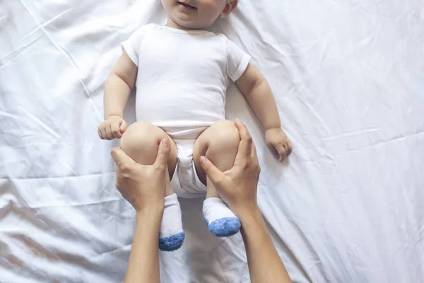 Baby massage. Mam doen gymnastiek met Kid. Mama masserende schattige baby jongen. Bewegende baby's benen om constipatie te helpen verlichten. Jonge moeder doet oefeningen en bewegingen om baby's darmen te stimuleren. — Stockfoto