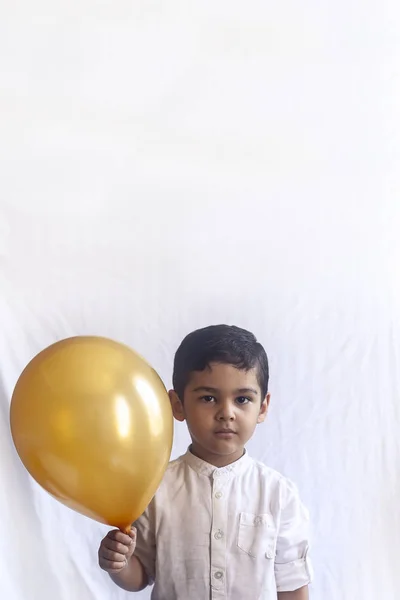 Retrato de niño de 5-6 años con globo. Adorable chico de Oriente Medio sosteniendo un globo dorado. Celebración, concepto de vacaciones . — Foto de Stock