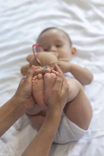 Baby massage. Mamma gör gymnastik med Kid. Mamma massera söt baby boy. Rörliga barnets ben för att hjälpa till att lindra förstoppning. Ung mamma gör övningar och rörelser för att stimulera barnets tarmar. — Stockfoto