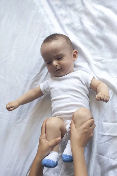 Massage bébé. Maman fait de la gymnastique avec un gosse. Maman massant mignon bébé garçon. Déplacer les jambes du bébé pour aider à soulager la constipation. Jeune mère faisant des exercices et des mouvements pour stimuler les intestins du bébé . — Photo