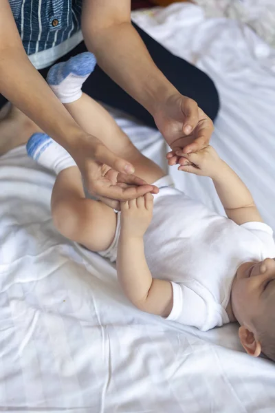 Baby massage. Mom doing gymnastics with kid. Mommy massaging cute baby boy. Moving baby's legs to help relieve constipation. Young mother doing exercises and movements to stimulate baby's bowels. — Stock Photo, Image