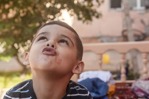 El niño contornea su cara al aire libre. Niño de 6 años en vacaciones de verano. Lindo niño haciendo el tonto. Gente, concepto de estilo de vida infantil. Retrato de un niño haciendo caras graciosas — Foto de Stock