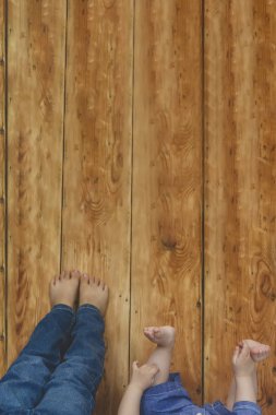 İki genç kardeş yataklarında yatıyor. Çocuklar eğleniyor. İki küçük kardeş bacaklarını tahta masaya doğru kaldırıyor..