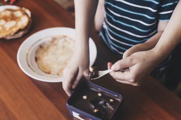 Annesiyle birlikte kahvaltı hazırlayan küçük bir çocuk. Anne ve oğlu ince krep çikolata krema bulaşması. Boş alan — Stok fotoğraf