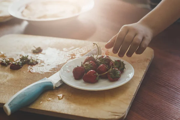 Ein kleiner Junge mit seiner Mutter, die gemeinsam ein Frühstück zubereitet. Mutter und Sohn schmieren Schokoladencreme zu dünnen Pfannkuchen. Freiraum — Stockfoto