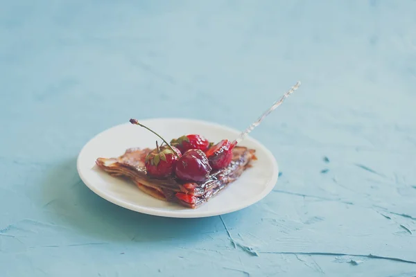 Pancake tipis dengan stroberi dan krim coklat. Pancake dengan stroberi segar di meja biru terang — Foto Stok Gratis