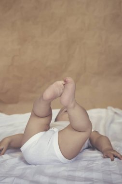 6-8 aylık erkek bebek yatakta eğlenceli bir şekilde yatıyor. Beyaz bodysuit büyüleyici 6-7 aylık küçük bebek. Beyaz yataklı bebek. Kopyalama alanı