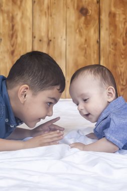 Mutlu çocukluk konsepti. Mutlu kardeşler portresi. 6 yıl 6 aylık çocuklar eğleniyor. İki küçük çocuk iyi vakit geçirerek gülümsüyor. Sevimli küçük kardeşler yalan ve birlikte oynuyor
