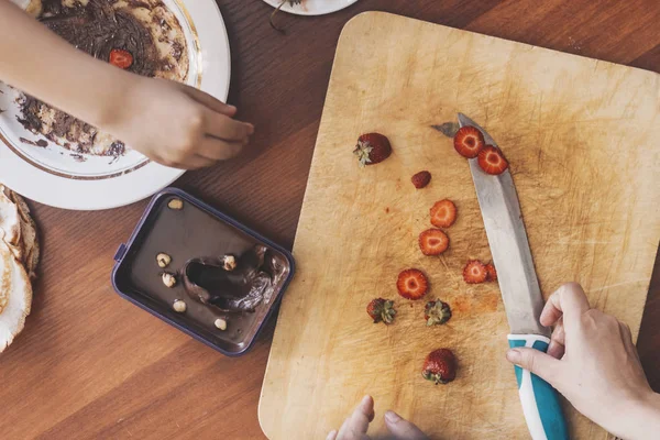 Un niño pequeño con su madre preparando juntos un desayuno. Madre e hijo untando crema de chocolate a tortitas finas. Espacio libre — Foto de Stock