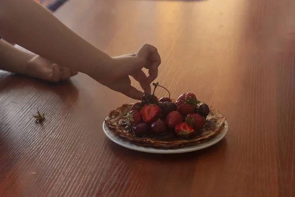 En liten pojke som äter jordgubbar. Sommar mat. En ung unge äter en smaskig jordgubb i varm sommardag — Stockfoto