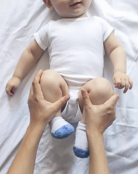 Baby massage. Mam doen gymnastiek met Kid. Mama masserende schattige baby jongen. Bewegende baby's benen om constipatie te helpen verlichten. Jonge moeder doet oefeningen en bewegingen om baby's darmen te stimuleren. — Stockfoto