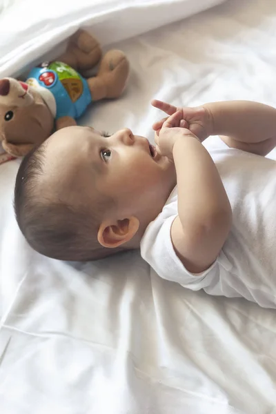 6-8-maand-oude baby jongen liggend spelvol in bed. Charmante 6-7 maand kleine baby in witte Romper. Baby jongen in wit beddengoed. Ruimte kopiëren — Stockfoto