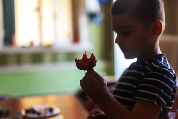 Un niño comiendo fresas. Comida de verano. Un niño pequeño come una deliciosa fresa en un caluroso día de verano. — Foto de Stock