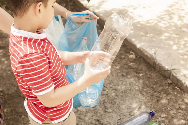 Mère et fils ramassant des bouteilles en plastique. La famille porte un sac poubelle. Pollution plastique sur terre . — Photo