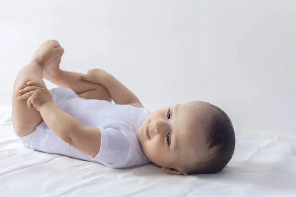 6-maanden baby met plezier in wit beddengoed. Schattige baby liggend op bed. Familie, nieuw leven, jeugd concept. — Stockfoto