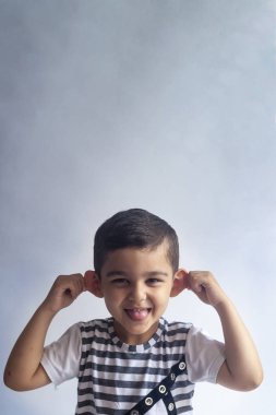 Altı yıllık çocuk portre. Gri arka planda masum gülümseyen küçük çocuk. Küçük çocuk yüzünü kontrol eder. İnsanlar, çocukluk yaşam tarzı kavramı.