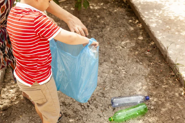 Poluição plástica em terra. Rapaz a recolher garrafas de plástico. O miúdo leva o saco do lixo. Espaço livre — Fotografia de Stock